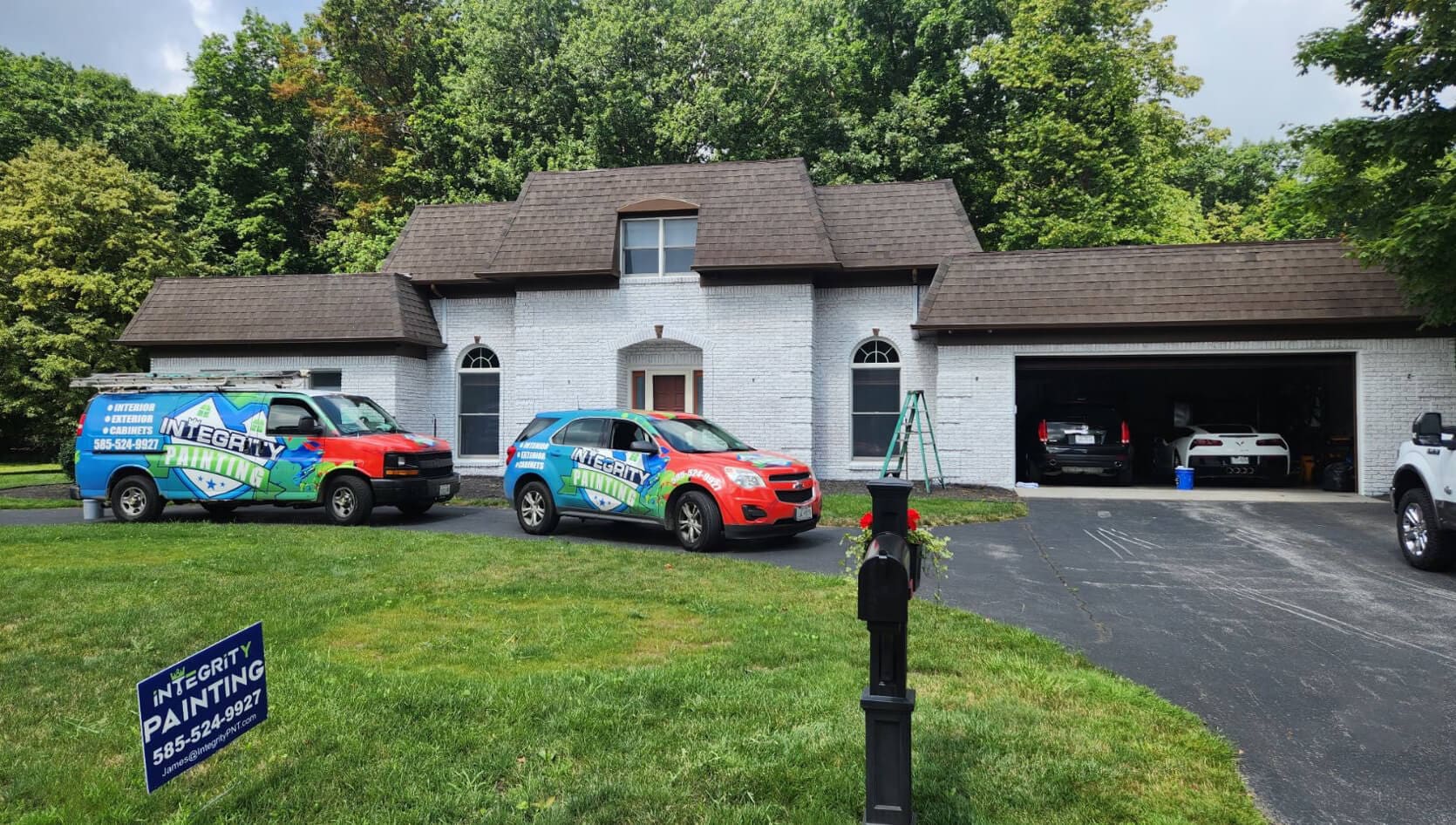 integrity painting wrapped work trucks in front of home that was just painted